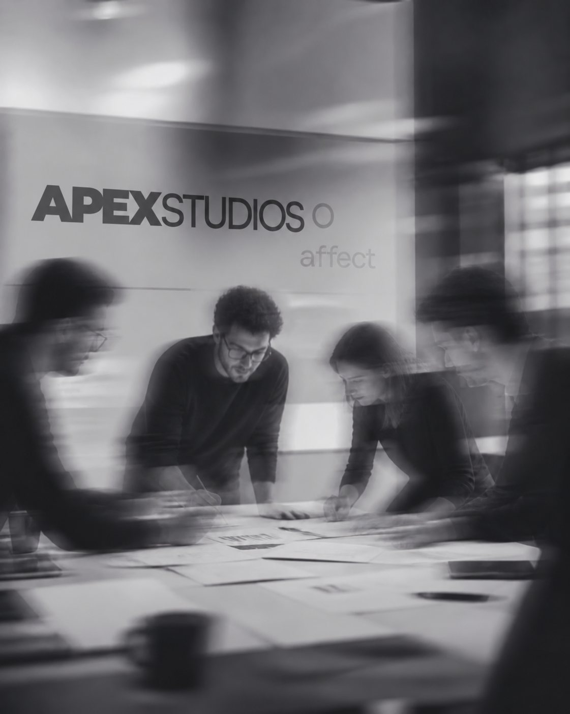 ApexStudios ekibi, APEXSTUDIOS yazılı duvarın önünde masa başında birlikte çalışıyor